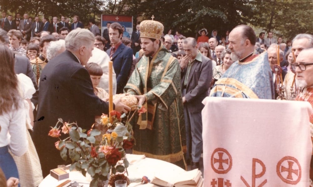 Bishop Lavrentije cutting the bread in front of the church on Vidovdan